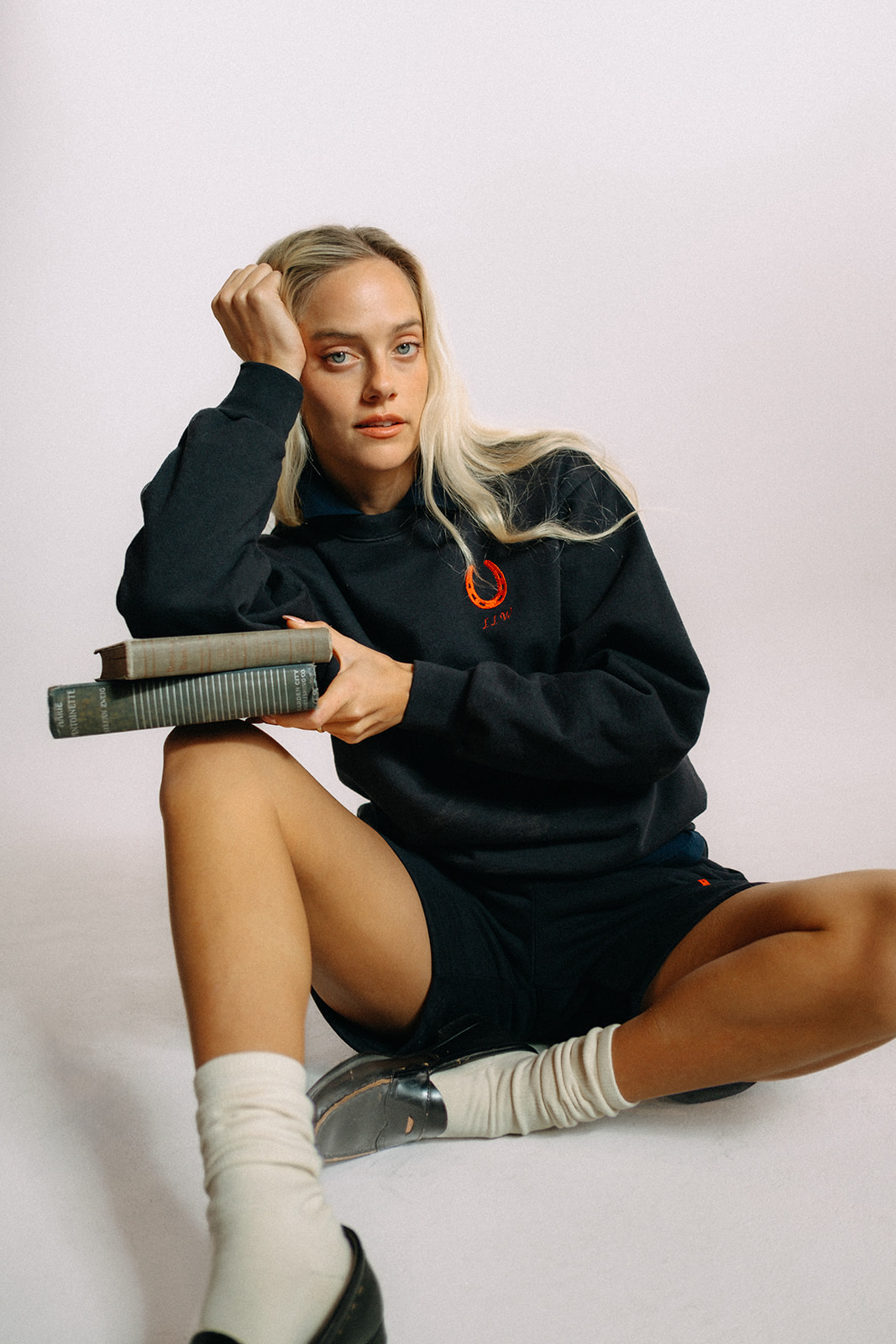 Woman wearing a navy blue sweater with a red embroidered horseshoe